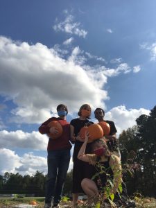 Lizzy and her housemates holding pumpkins in a field